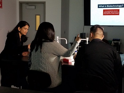 A female instructor overseeing two students at a laboratory station